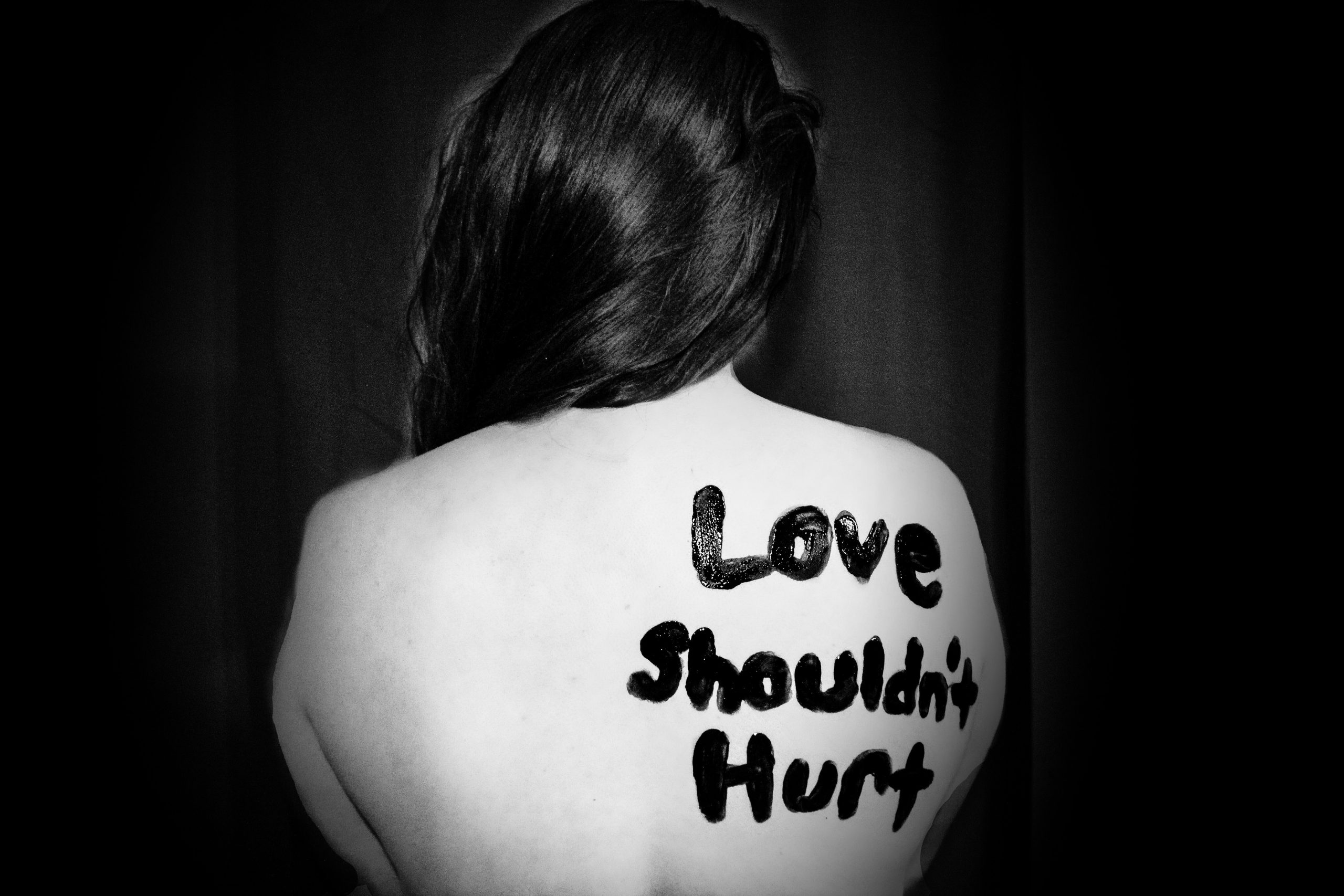 A woman with the words "Love Shouldn't Hurt" written on her back