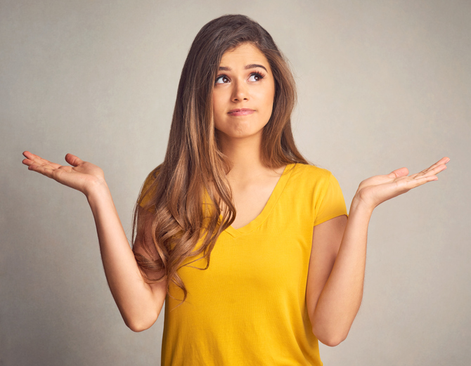 Girl in yellow shirt holding her hands up by her sides. 