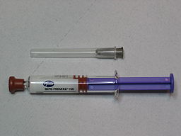 Needle and body of syringe laid out side by side.