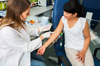 A health care provider pointing to a patient's inner arm where blood will be drawn.